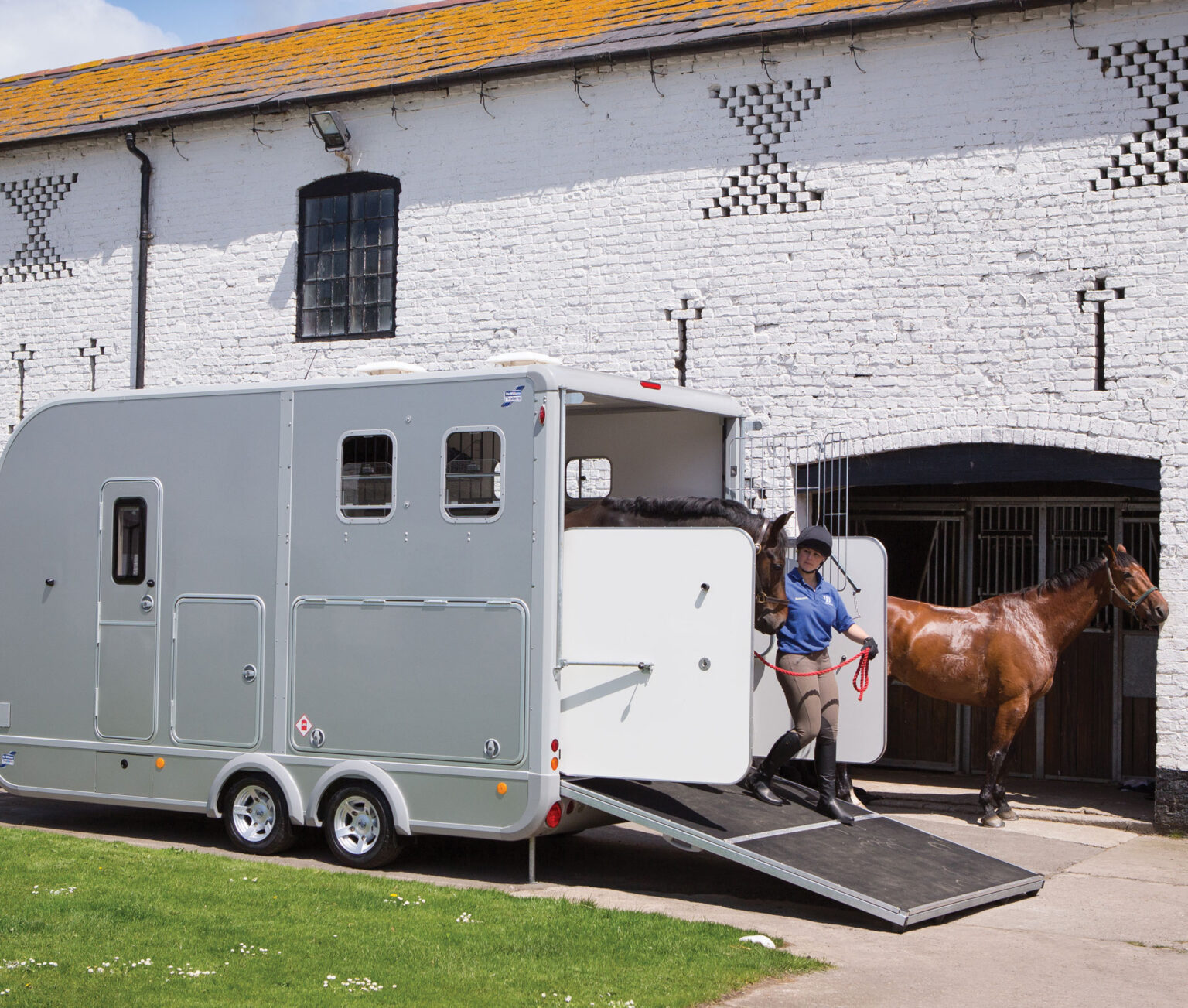 Eventa Medium horse trailer unloading a dark bay horse with a handler